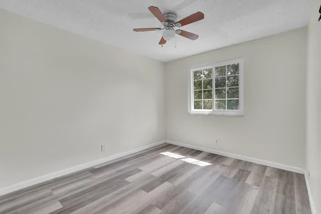 an empty room with a window and a ceiling fan