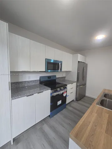 a kitchen with granite countertop a refrigerator and a stove top oven
