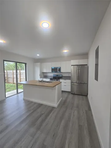 a large kitchen with stainless steel appliances granite countertop a stove a refrigerator a sink dishwasher and a oven with wooden floor