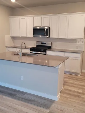 a kitchen with stainless steel appliances granite countertop a sink a stove and a microwave