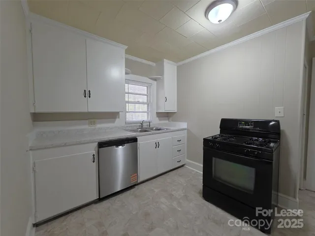 a kitchen with granite countertop white cabinets and stainless steel appliances