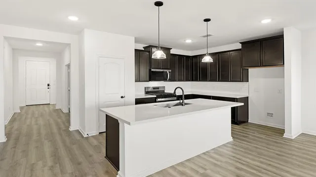 a kitchen with a sink and a stove top oven with wooden floor