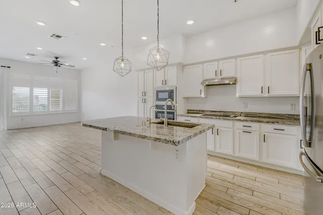 a kitchen with stainless steel appliances granite countertop a sink a stove and a wooden floors