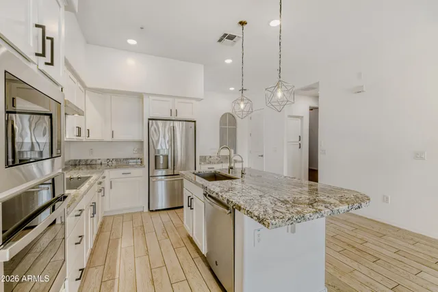 a kitchen with a sink a counter top space stainless steel appliances and cabinets