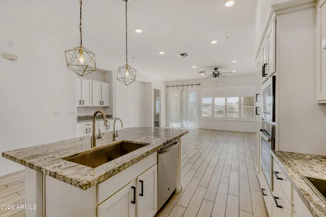 a kitchen with granite countertop a sink a counter space appliances and cabinets