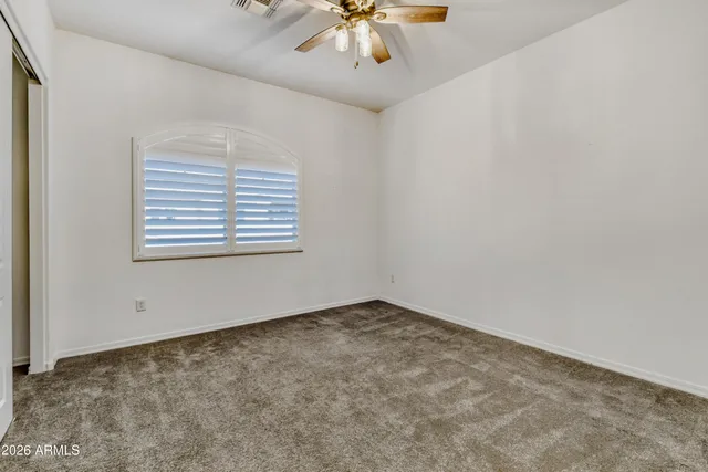 an empty room with a chandelier fan and windows