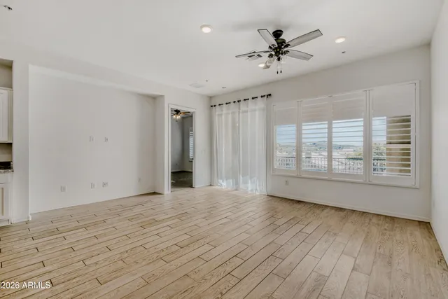a view of an empty room with a window and wooden floor