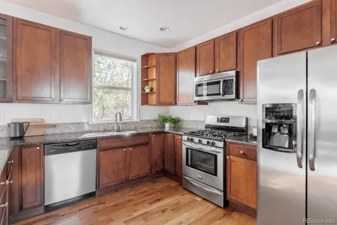 a kitchen with stainless steel appliances granite countertop a stove top oven a sink and dishwasher a oven with wooden floors