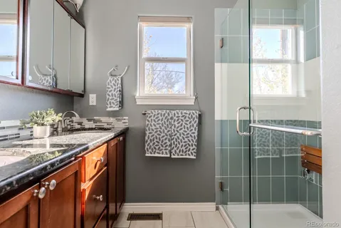 a bathroom with a granite countertop sink a mirror and next to a window