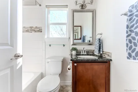 a bathroom with a granite countertop sink toilet and mirror