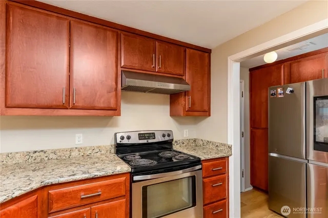 a kitchen with stainless steel appliances granite countertop a stove a sink and a microwave