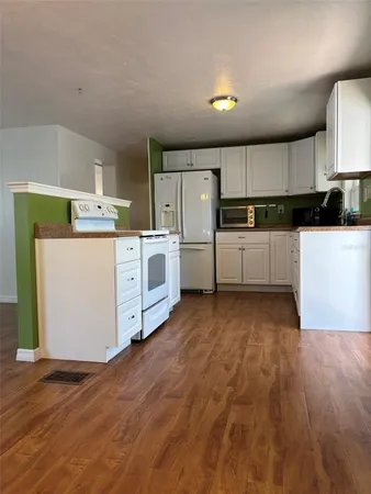a kitchen with cabinets wooden floor and stainless steel appliances