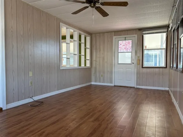 an empty room with wooden floor fan and windows