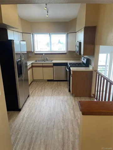 a kitchen with stainless steel appliances granite countertop a refrigerator a sink dishwasher a stove and white countertops with wooden floor