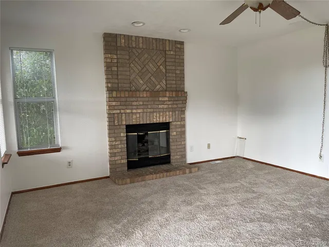 an empty room with windows and fireplace