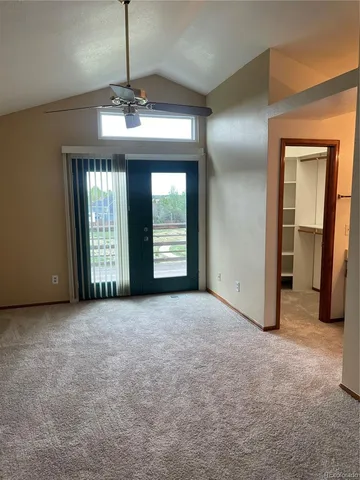 an empty room with chandelier fan and windows