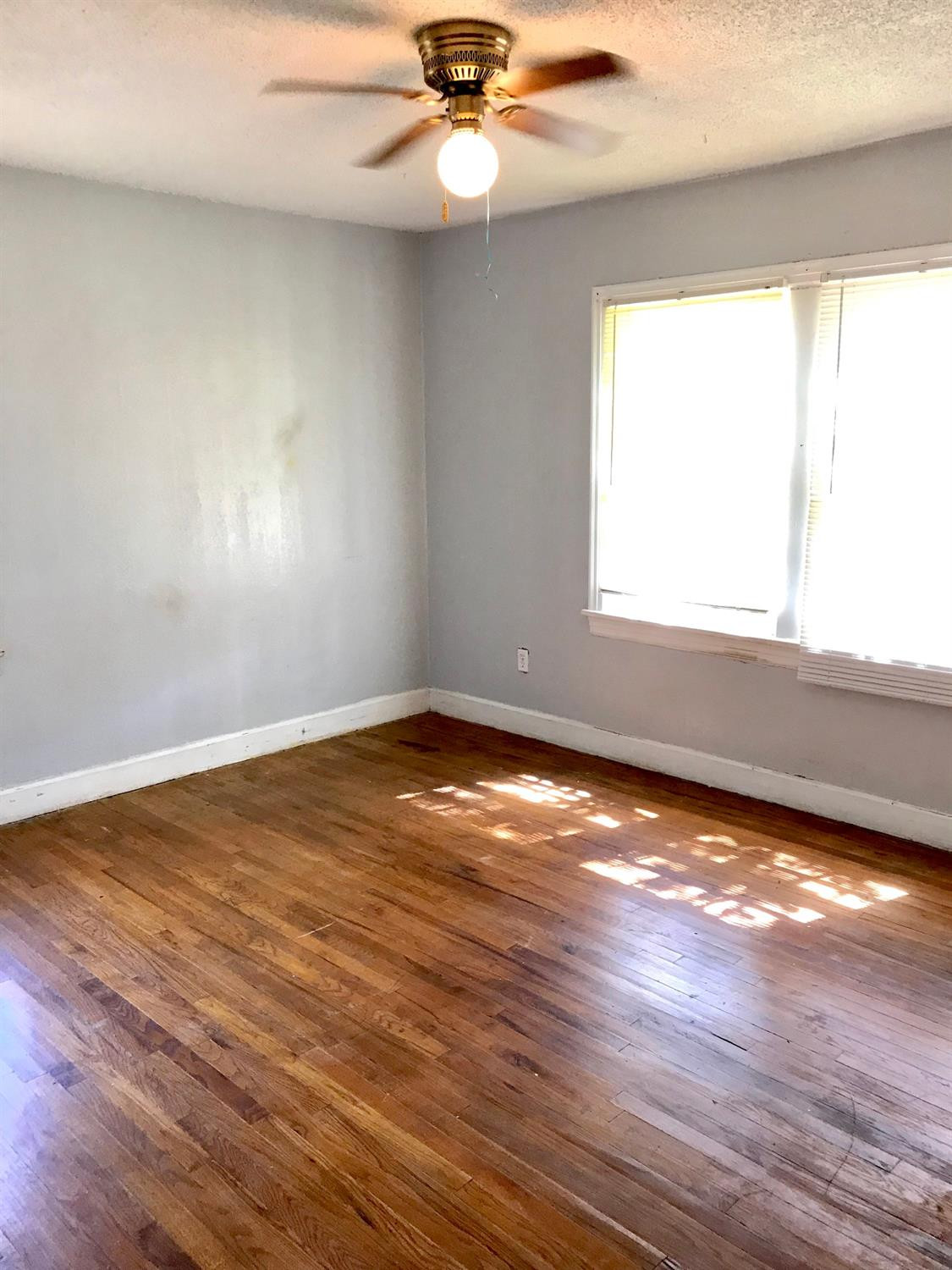 3016 30th Street Lubbock, TX 79410 - Photo 6 of 8 an empty room with wooden floor a ceiling fan and window