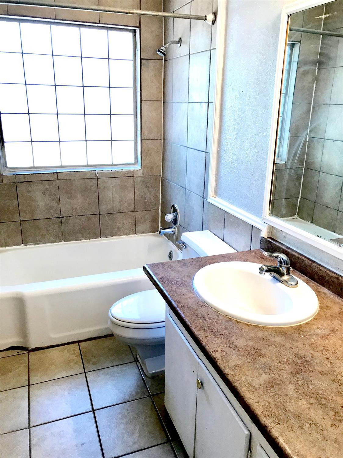 3016 30th Street Lubbock, TX 79410 - Photo 7 of 8 a bathroom with a granite countertop sink a toilet a mirror and bathtub
