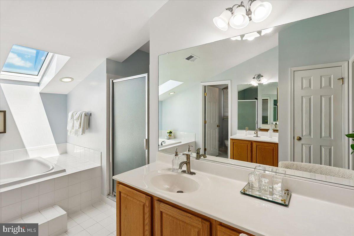9909 Midsummer Snow Lane Laurel, MD 20723 - Photo 34 of 81 a bathroom with a sink a large mirror and a bathtub