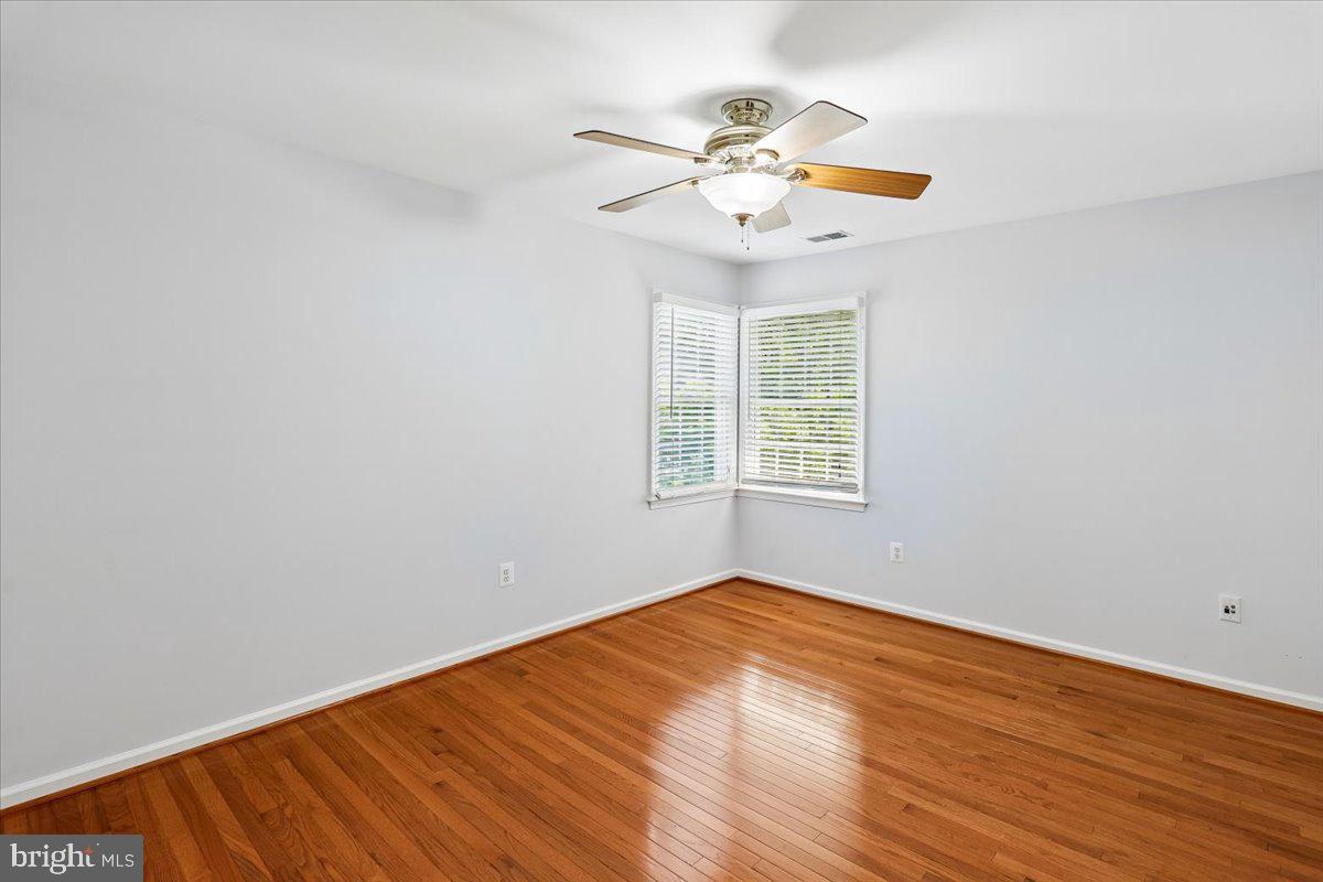 9909 Midsummer Snow Lane Laurel, MD 20723 - Photo 39 of 81 an empty room with wooden floor chandelier fan and windows
