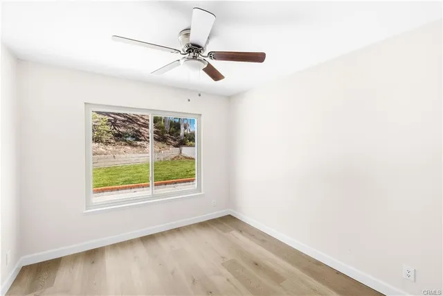 an empty room with a window and a ceiling fan