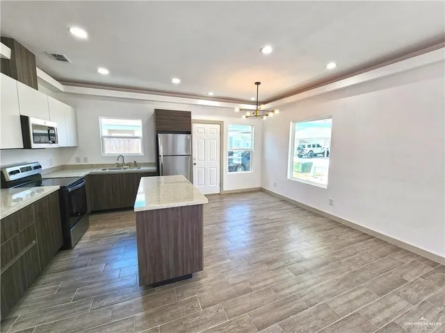 a large kitchen with wooden floors and stainless steel appliances