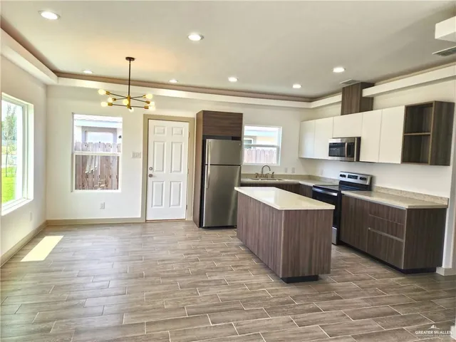 a large kitchen with stainless steel appliances granite countertop a stove and a refrigerator