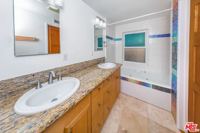 a bathroom with a granite countertop tub sink and mirror