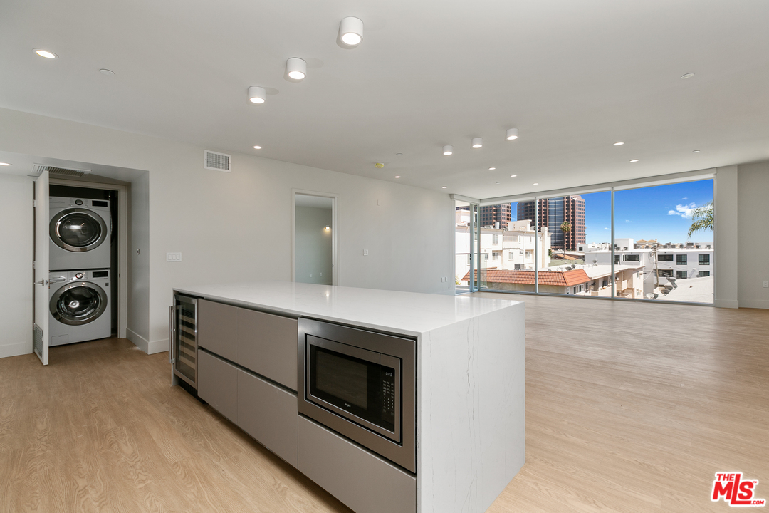 a view of living room with stainless steel appliances wooden floor and window