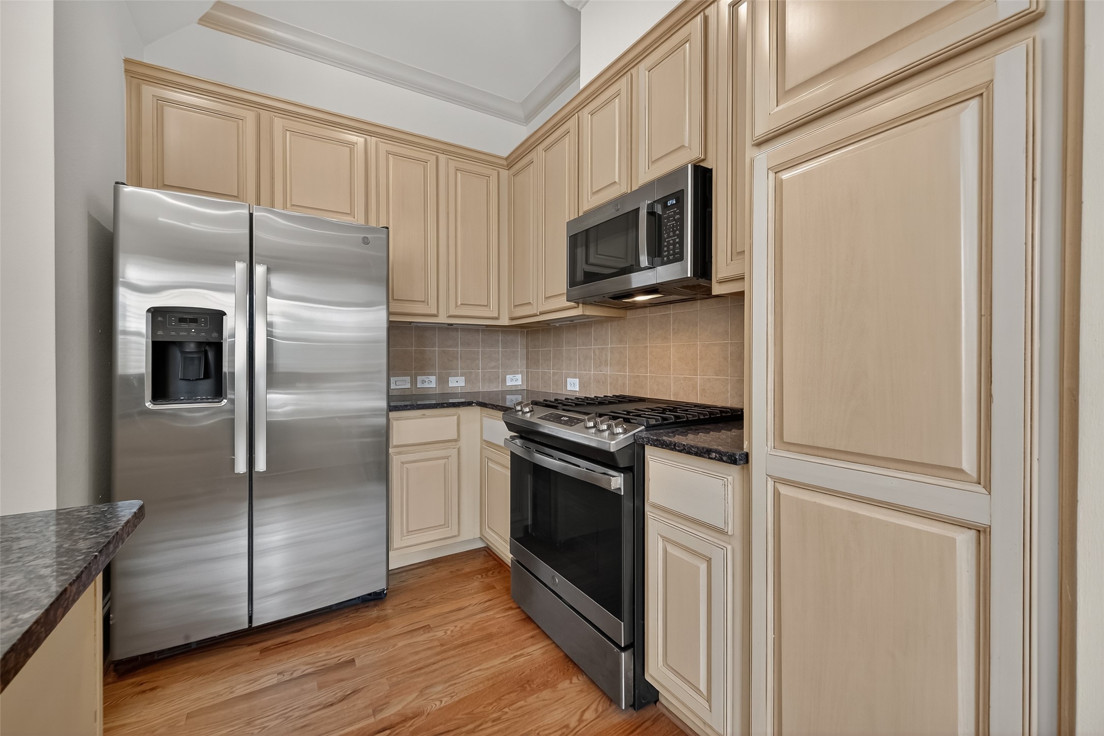 931 West 23rd Street, Unit K Houston, TX 77008 - Photo 10 of 40 14'2" x 14'9" kitchen is complete with GE Profile stainless microwave (2021), GE Profile stainless gas oven (2021), GE Profile stainless refrigerator, GE Profile stainless dishwasher (2025), raised center cabinets, tile backsplash, double basin undermount sink and brushed nickel faucet.