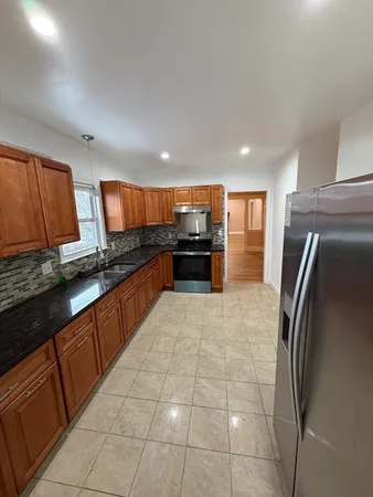 a large kitchen with stainless steel appliances granite countertop a refrigerator and a stove top oven
