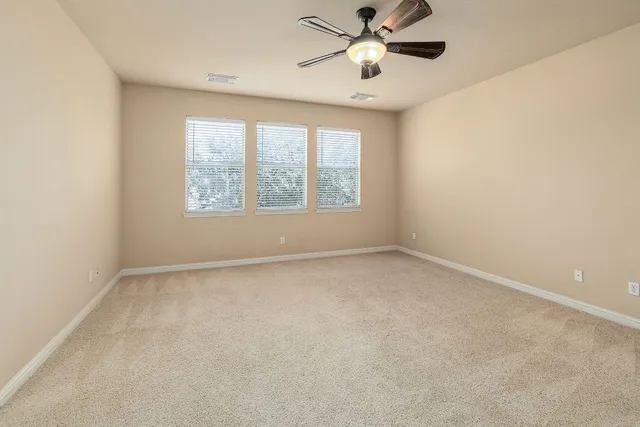 an empty room with a window and a fan