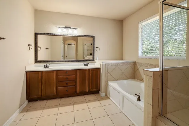 a spacious bathroom with a tub sink and mirror