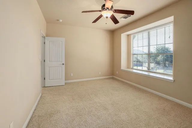 an empty room with windows and fan