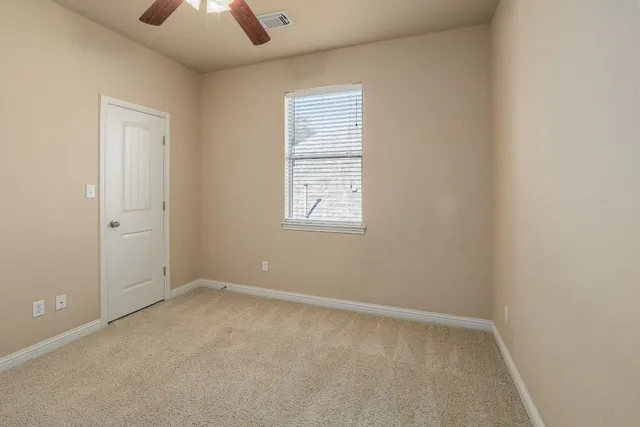 an empty room with a window and a ceiling fan