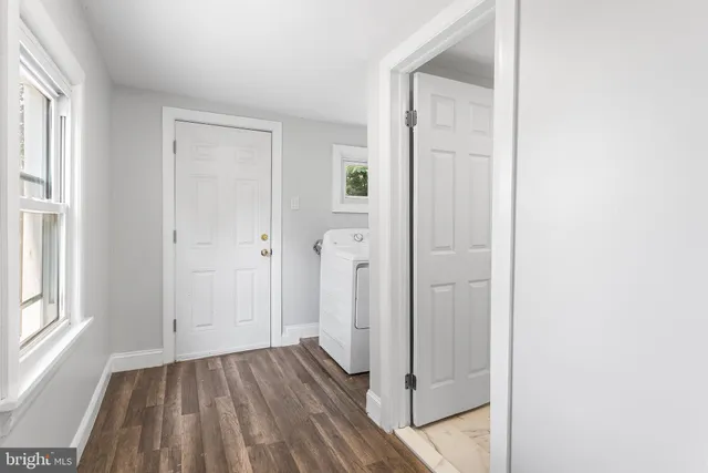 a view of a hallway with wooden floor and a bathroom
