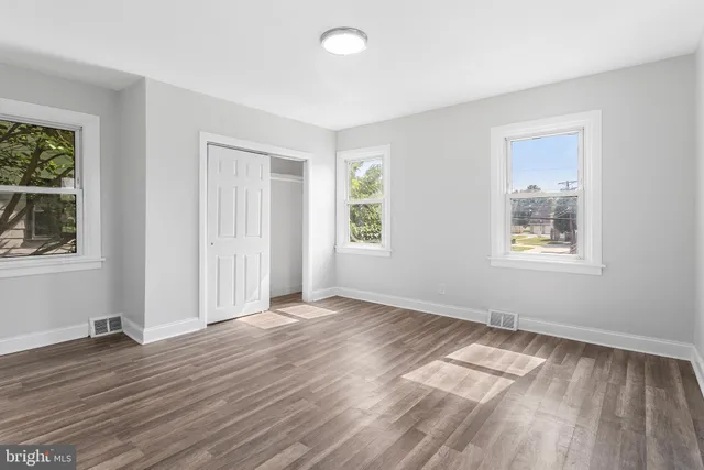 a view of an empty room with window and wooden floor