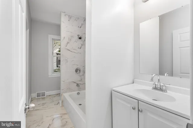 a bathroom with a granite countertop sink a toilet and shower