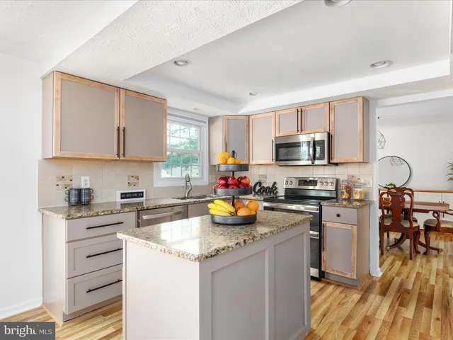 a kitchen with stainless steel appliances granite countertop a stove top oven a sink dishwasher and white cabinets with wooden floor