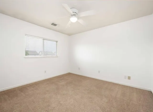 an empty room with a window and a fan