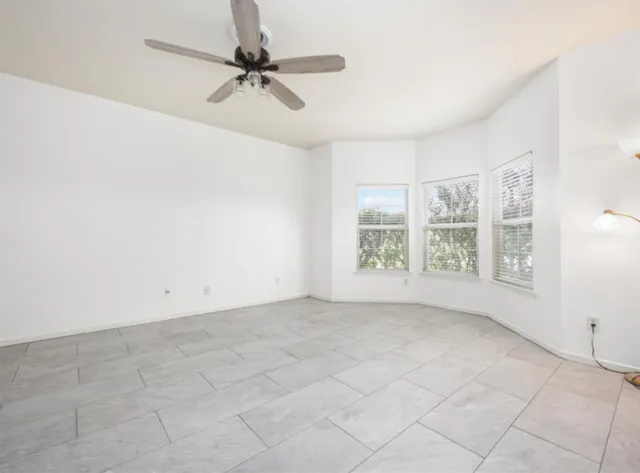 an empty room with windows and ceiling fan