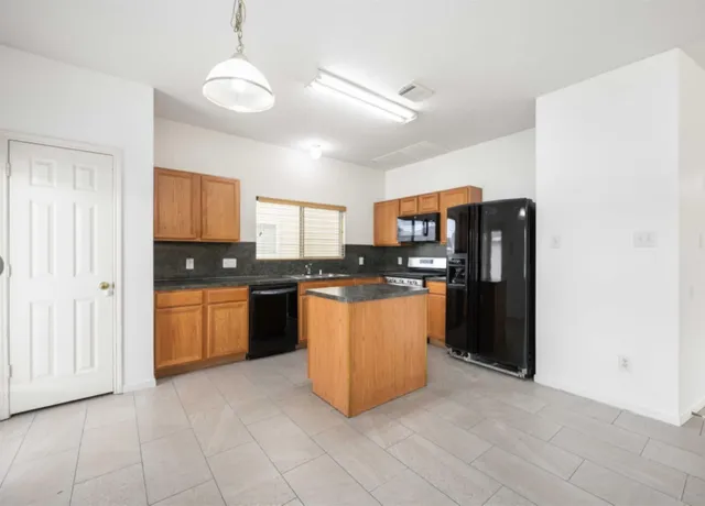 a kitchen with stainless steel appliances granite countertop a refrigerator a sink a stove a microwave and island