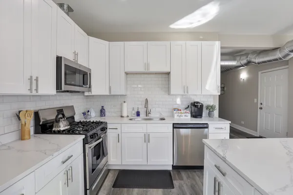 a kitchen with cabinets appliances a sink and a counter top space