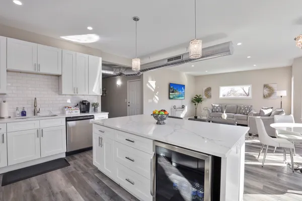 a kitchen with a sink dishwasher a stove a dining table and chairs with wooden floor