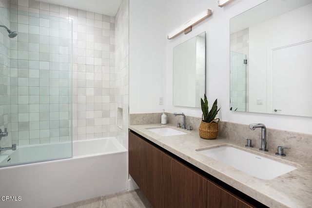 a bathroom with a granite countertop sink a mirror a bathtub and shower