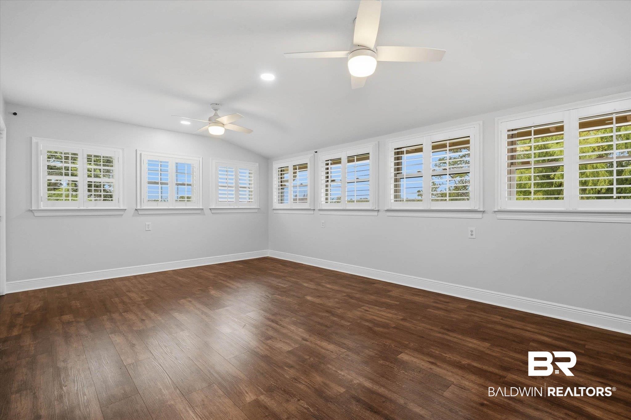 3801 Point Road Mobile, AL 36619 - Photo 17 of 55 Spacious room featuring wood-finish flooring, white baseboards, and numerous windows with white plantation shutters