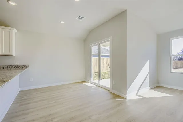 an empty room with a fireplace and windows