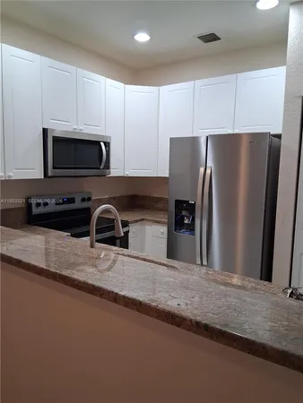 a kitchen with stainless steel appliances granite countertop a refrigerator a stove a sink and a granite counter tops