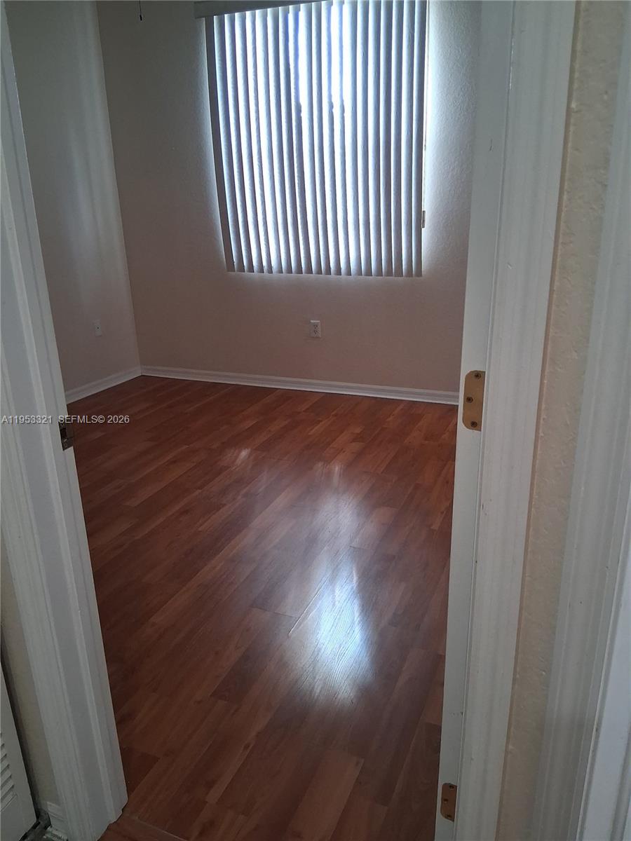 3395 Merrick Court, Unit 1110 Margate, FL 33063 - Photo 11 of 16 an empty room with wooden floor and windows