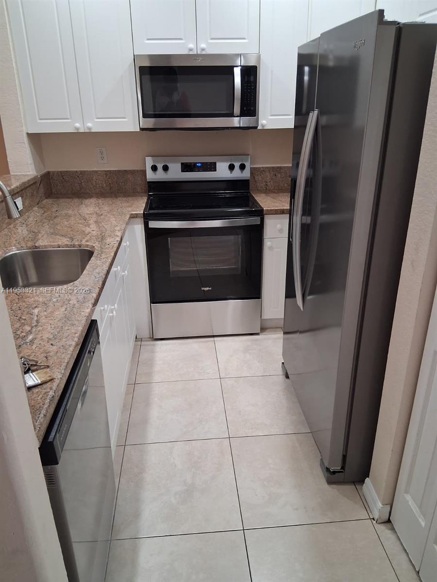 3395 Merrick Court, Unit 1110 Margate, FL 33063 - Photo 2 of 16 a kitchen with granite countertop a refrigerator and a sink